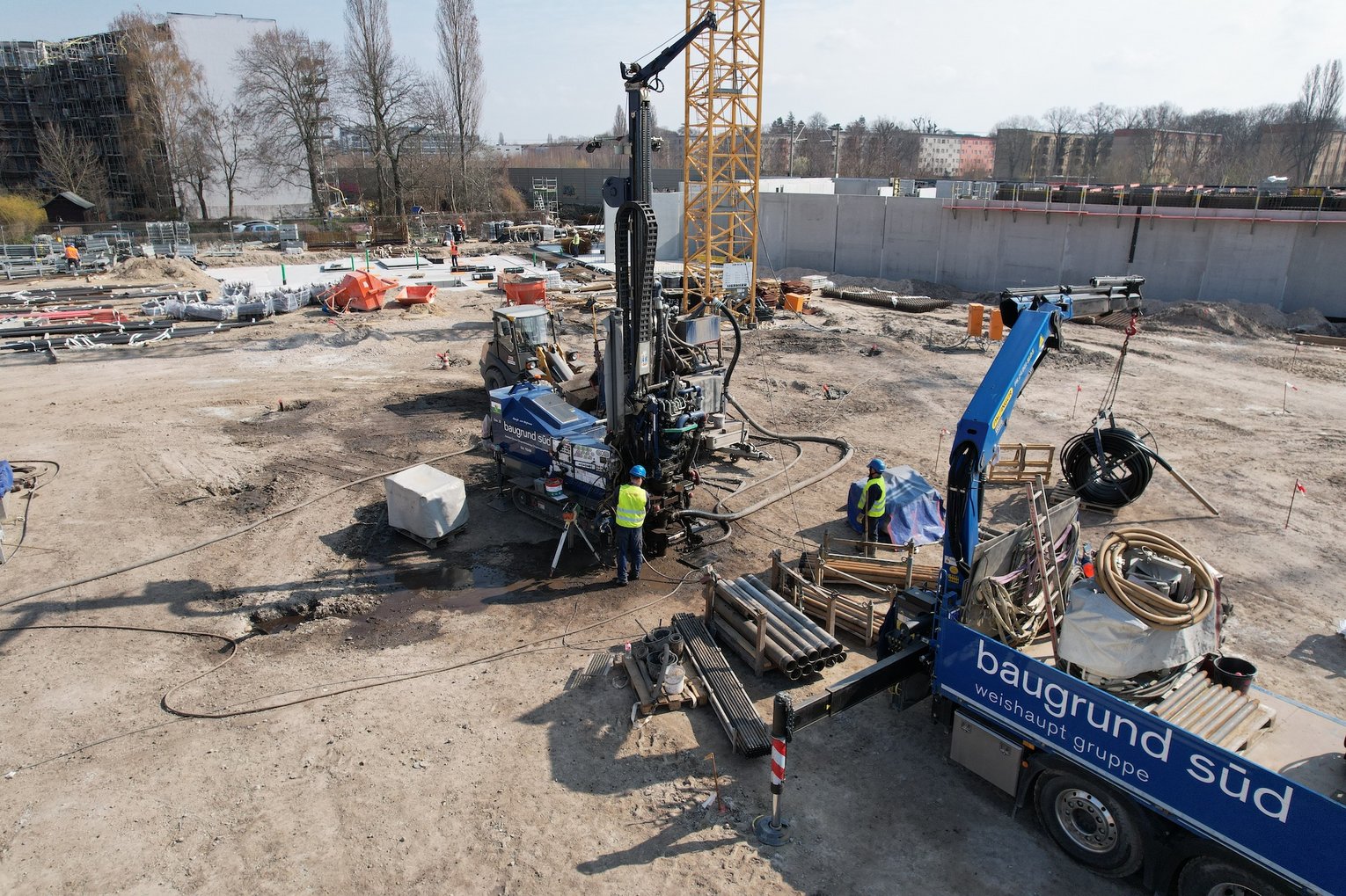 Baugrund Süd führt mit Bohrgerät, Mobilkran und Fachkräften Spezialtiefbauarbeiten auf einer großen Baustelle durch.