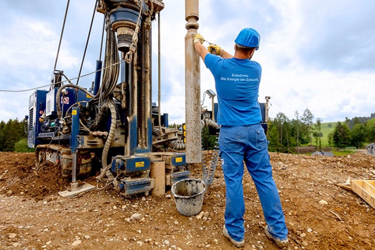 Mitarbeiter von BauGrund Süd steht auf einer Baustelle neben einer Bohrmaschine und kontrolliert den Arbeitsablauf.