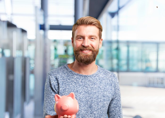 Person mit einem Sparschwein lächelt in die Kamera.