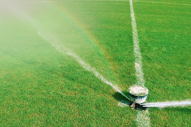 Ein Sprinkleranlage bewässert einen Rasen auf einem Sportplatz