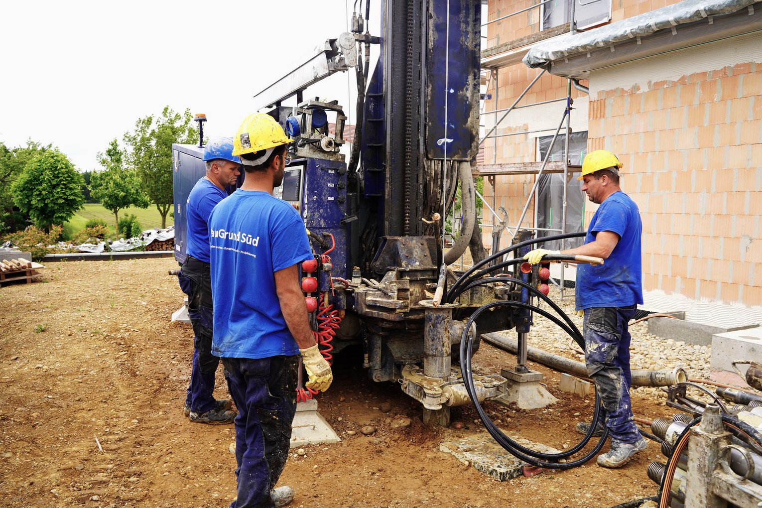Mehrere Mitarbeiter von BauGrund Süd bedienen einen Bohrer für Erdsonden auf einer Baustelle