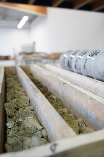 Bodenproben in Holzkisten mit beschrifteten Probenbehältern in einem geotechnischen Labor